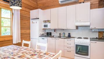 Cocina compacta con armarios blancos, horno integrado y microondas.