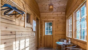 L’intérieur d’un chalet en bois comprend un coin repas avec des chaises, une table et un luminaire suspendu.