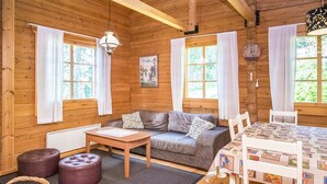 L’intérieur chaleureux d’un chalet avec un canapé, une table et des chaises, des murs en bois et de grandes fenêtres.
