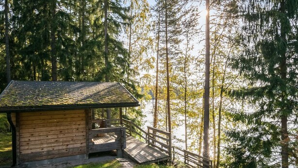 Une cabane avec une façade en bois, une véranda et un escalier menant à l’entrée.