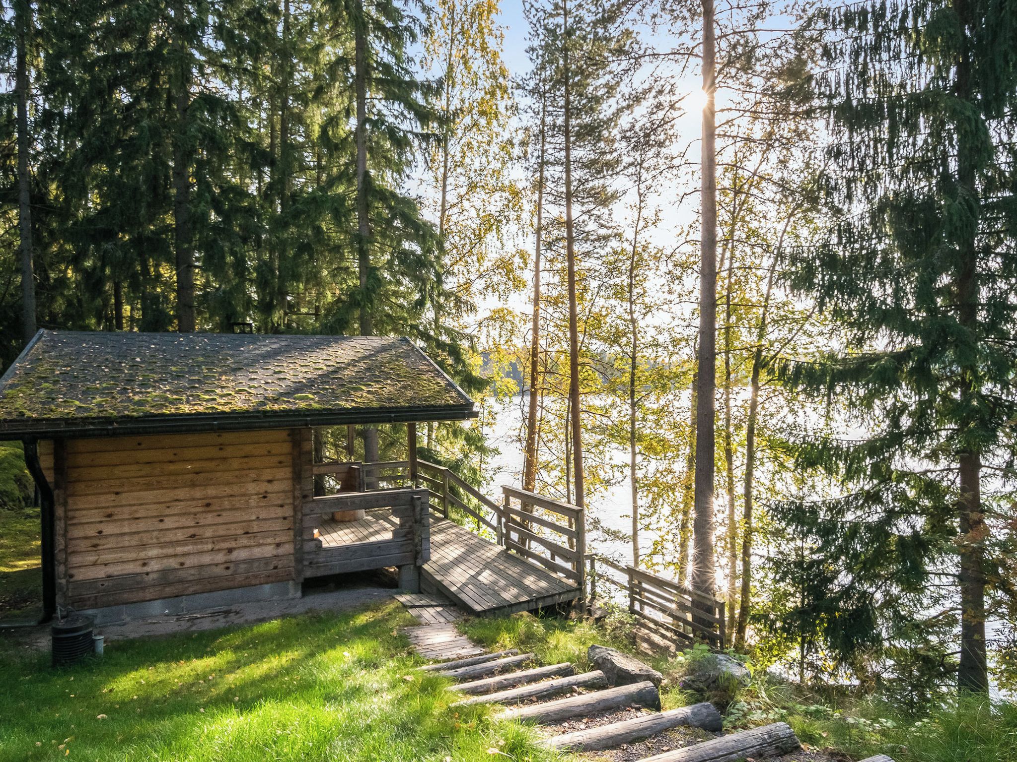 A wooden cabin with a wooden deck and stairs leading to a platform.