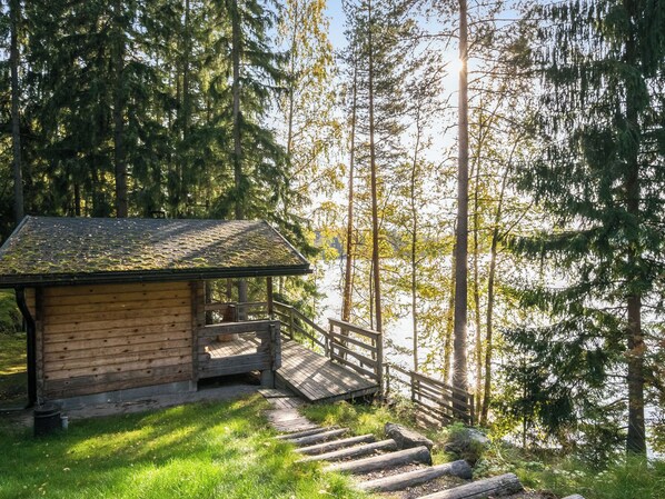 A wooden cabin with a wooden deck and stairs leading to a platform.