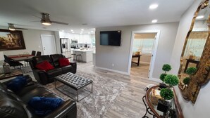 A modern living room with a black leather sofa, a coffee table, and a large mirror. - Quiet Neighborhood and close to all Tampa offers (Tampa)