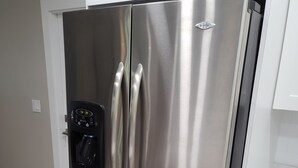 A stainless steel refrigerator with a digital control panel, located in a kitchen with white cabinetry and a wooden floor. - Quiet Neighborhood and close to all Tampa offers (Tampa)