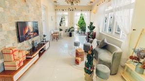 Amplia sala de estar con una televisión de pantalla plana, chimenea, sofá y árbol de Navidad.