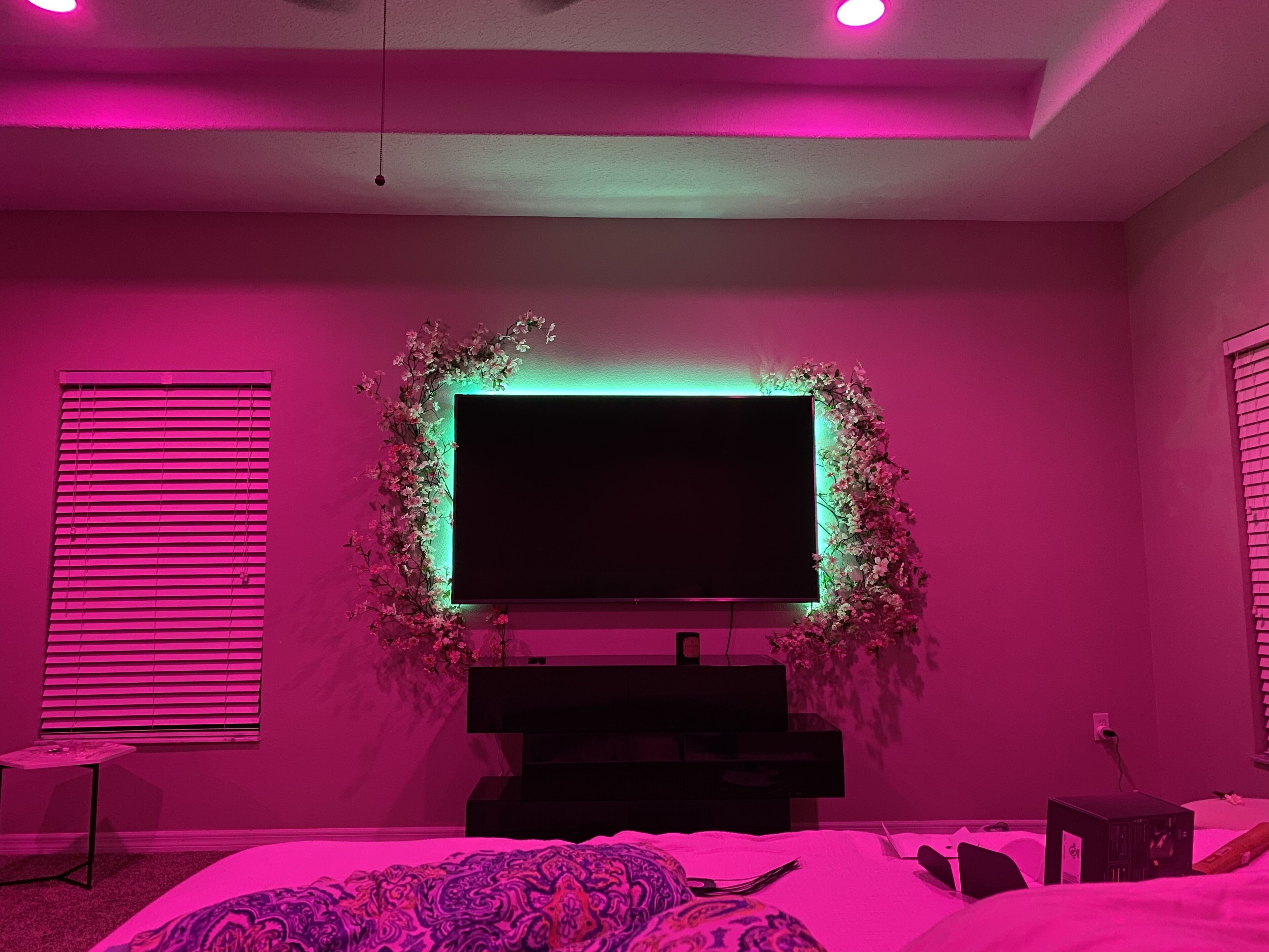 Un dormitorio con un televisor grande montado en la pared, rodeado de un arreglo floral.