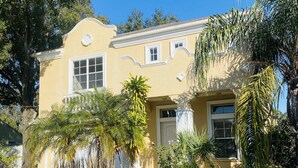 A two-story house with a yellow facade, white trim, and multiple windows. - Walk to Super Bowl LV! Grand Spanish Style Home (Tampa)