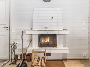 Une cheminée avec un manteau orné de carreaux, une enseigne au-dessus et des bûches devant.