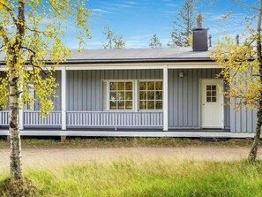 Une maison de plain-pied avec un porche, une cheminée et une porte portant un numéro.