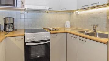 Una cocina compacta equipada con estufa, horno, microondas y cafetera.