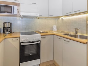 Una cocina compacta equipada con estufa, horno, microondas y cafetera.