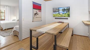 A modern room with a wooden table, a bed, and a painting of a lake.