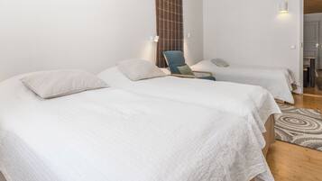 Habitación de hotel con dos camas, una silla, un tapete y una lámpara fijada a la pared.