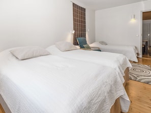 Habitación de hotel con dos camas, una silla, un tapete y una lámpara fijada a la pared.