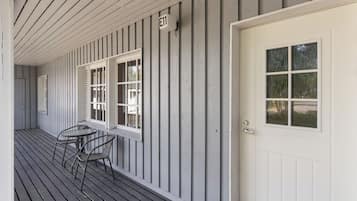 En bygning med facade, hvid dør, postkasse og et bord med stole på verandaen.