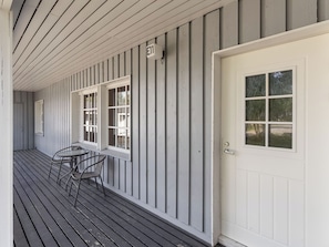 A building exterior with a white door, a mailbox, and a table with chairs on the porch. - Saariseläntie 8 e 11 by Interhome (Inari)