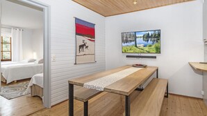 Una habitación moderna con una mesa de madera, una cama y un televisor en la pared.