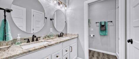 A bathroom with two sinks, a large mirror, and a vanity with drawers.