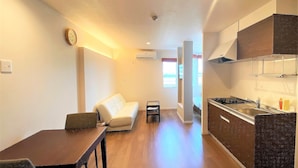 Un espacio habitable compacto con kitchenette, comedor y sofá.