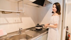 Una cocina moderna con electrodomésticos de acero inoxidable, un lavamanos doble y una persona cocinando.