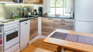 A modern kitchen with wooden cabinets, a built-in microwave, a stove, and a refrigerator. - Vuosselin kuukkeli by Interhome (Kuusamo)