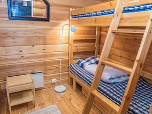 Une chambre avec un lit superposé en bois, un bureau et une lampe.
