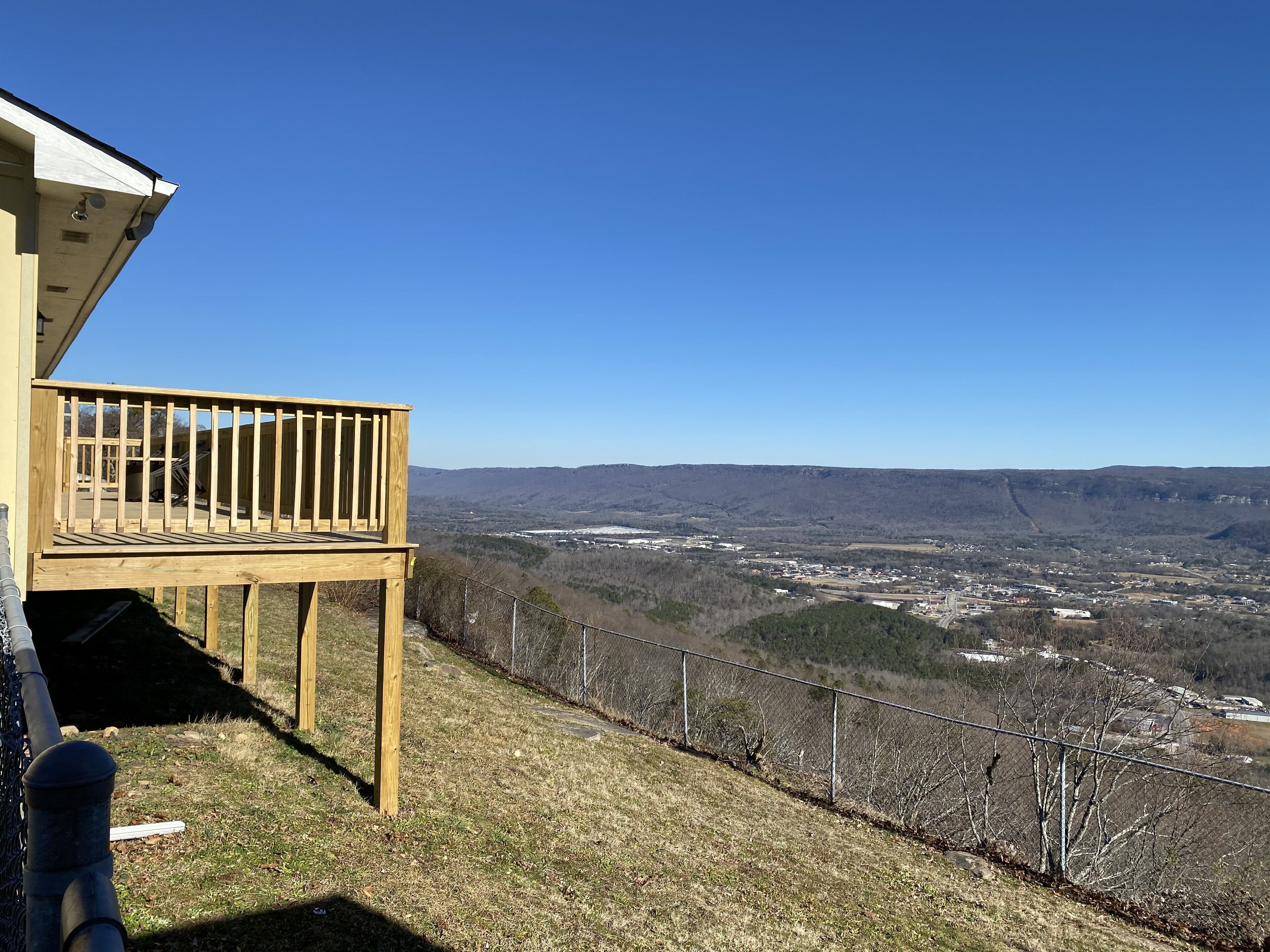 A wooden deck with a clear view of a valley and distant buildings.