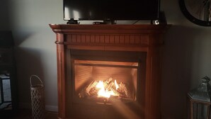 A living room with a fireplace, a television mounted above it, and a clock on the wall. - Mountaintop View (Trenton)
