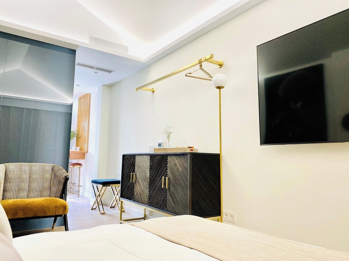 Una camera da letto moderna con un letto, una scrivania, una sedia e una TV.