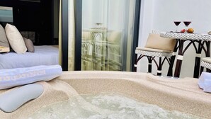 Une chambre à coucher avec un lit, une porte vitrée donnant sur un balcon et une petite table avec une chaise.