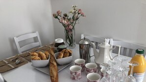 Une table dressée pour le petit-déjeuner, avec du pain, du café, du thé et du jus de fruits.