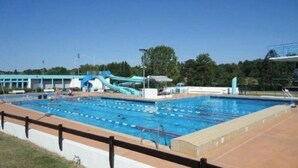 Une piscine avec des couloirs de nage, un toboggan aquatique et un espace abrité.