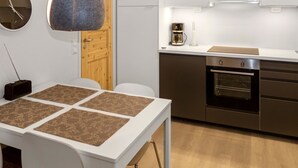 Eine moderne Küche mit weißen Schränken, einem eingebauten Ofen und einer Kaffeemaschine auf der Arbeitsfläche.