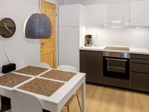 Cozinha moderna com bancada branca, eletrodomésticos de aço inoxidável e porta de madeira.