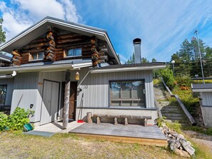 A log cabin with a wooden exterior, a chimney, and a set of stairs leading to the entrance.