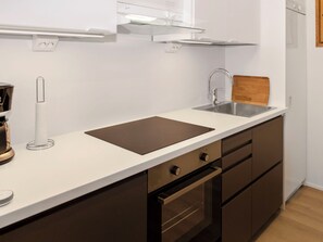 A modern kitchen with a stainless steel sink, a wooden cutting board, and a built-in oven.