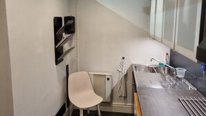 Een kleine keuken met een witte stoel, een spoelbak en een radiator.
