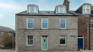 A two-story building with a green door, multiple windows, and a sign indicating "HIGH STREET".