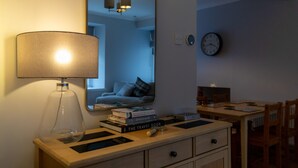 A room with a desk, a lamp, a mirror, a clock, and a bookshelf with books.