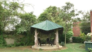 Ein Pavillon mit grüner Dachdeckung, umgeben von Rasen und Bäumen.