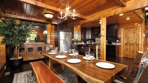 A wooden interior with a dining table set for four, a chandelier, and a large plant. - Patriots Den - Comfy Interiors, Cozy fireside nights, Wi-Fi and Porch Swings (Gatlinburg)