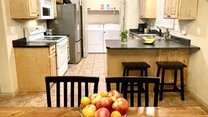 Une cuisine dotée de meubles en bois, d’un réfrigérateur, d’une cuisinière et d’un coin repas avec une table et des chaises.