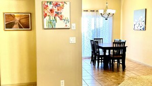 Un espace repas comprenant une table et des chaises, un lustre et des œuvres d’art accrochées aux murs.