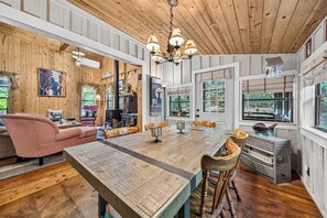 Un salon spacieux avec une grande table en bois, des sièges confortables et une cheminée.
