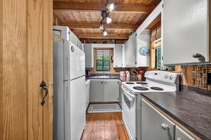 A kitchen with wooden ceiling beams, a refrigerator, a stove, and a sink. - Perfect Cabin Near Lake Rabun Beach, Beautiful Hikes, Waterfalls, Tallulah Gorge (Lakemont)