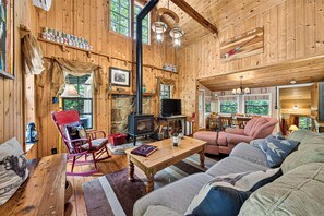 Un intérieur de chalet chaleureux avec une cheminée en pierre, des meubles en bois et un téléviseur.