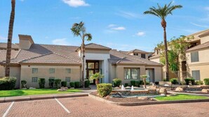 A residential building with a tiled roof, a central entrance, and a landscaped garden with palm trees and a fountain. - 2 Bd/2Ba in Central Phx with a private patio, 2 pools, 2 hot tubs gated complex! (Phoenix)