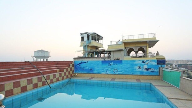 Piscina com um mural de golfinhos e uma torre de salva-vidas.
