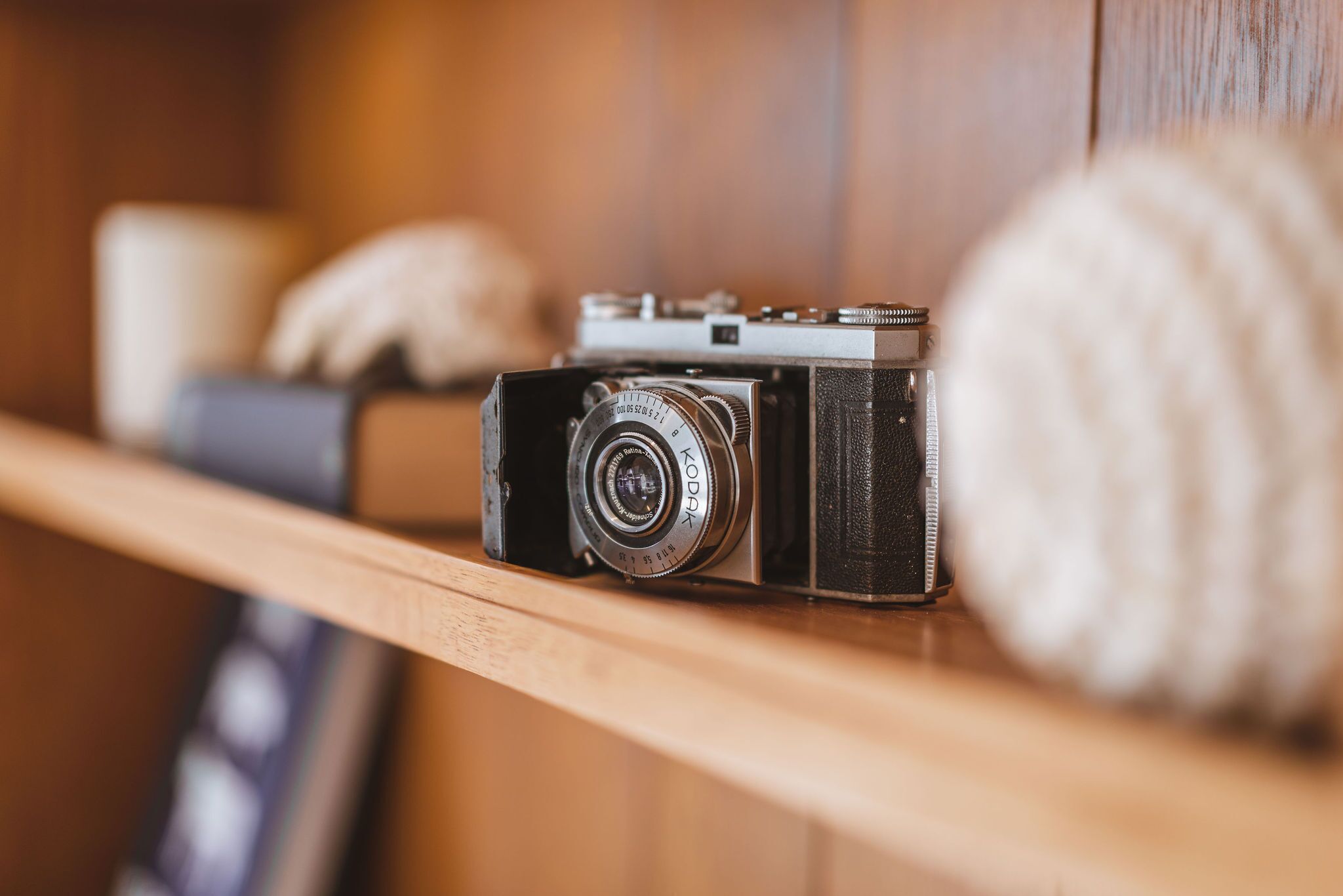 A vintage camera on a wooden shelf.