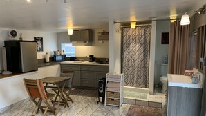 A modern kitchen with a dining area, a built-in oven, and a coffee machine.